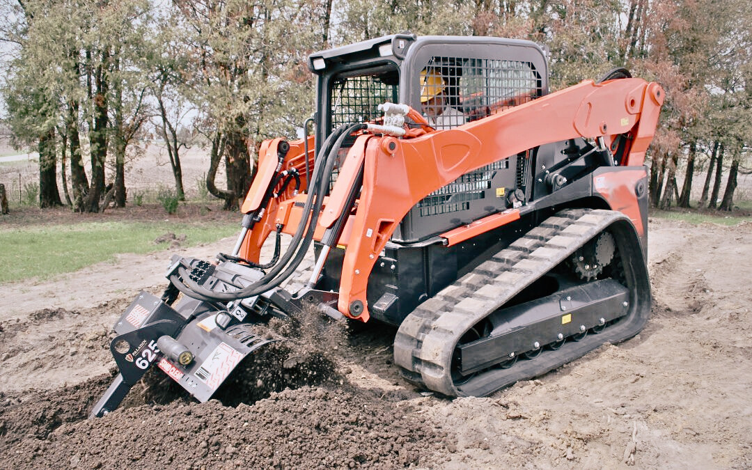 Skid steer bobcat from Dynamic Earth Solutions working on footings and trenches at a construction site.