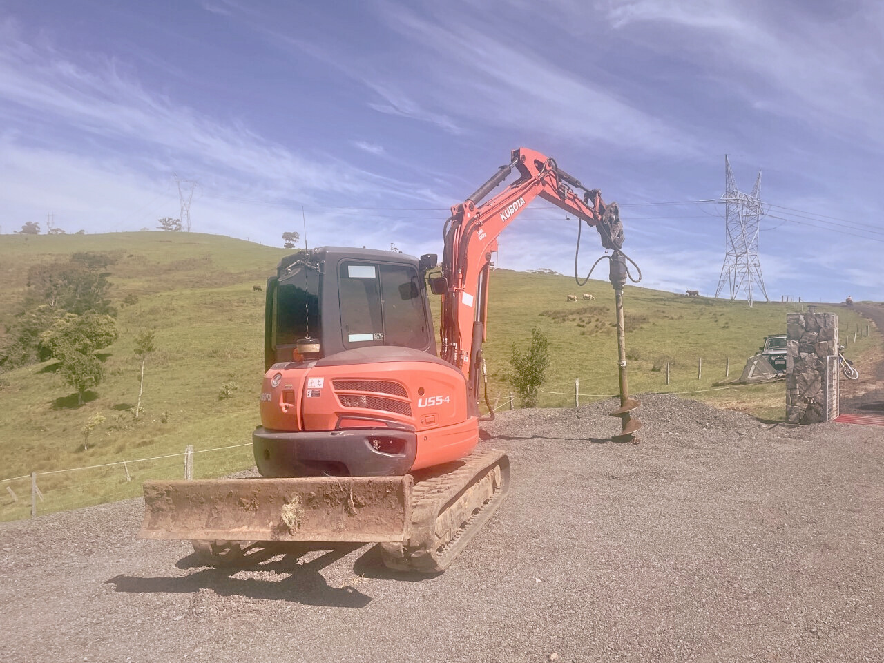 Excavator from Dynamic Earth Solutions equipped with an auger attachment performing hole boring.