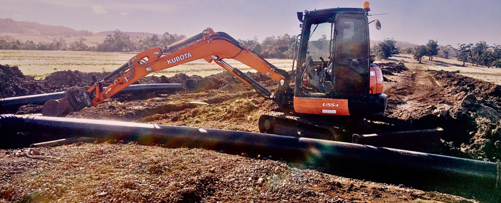 Dynamic Earth Solutions operator digging a drainage channel with an excavator.