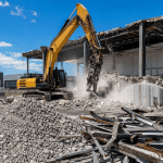 Excavator demolishing commercial warehouse in Salisbury Brisbane industrial estate with sorted materials