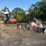 Excavator loading demolition debris onto a tipper truck on a cleared site