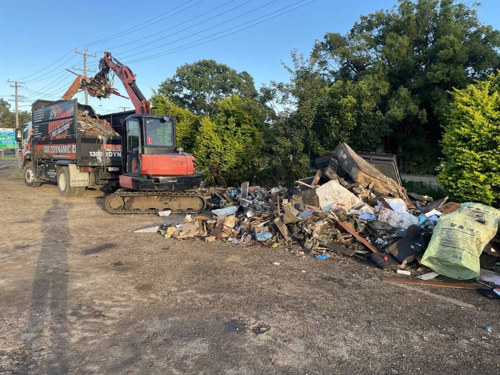 Excavator loading demolition debris onto a tipper truck on a cleared site